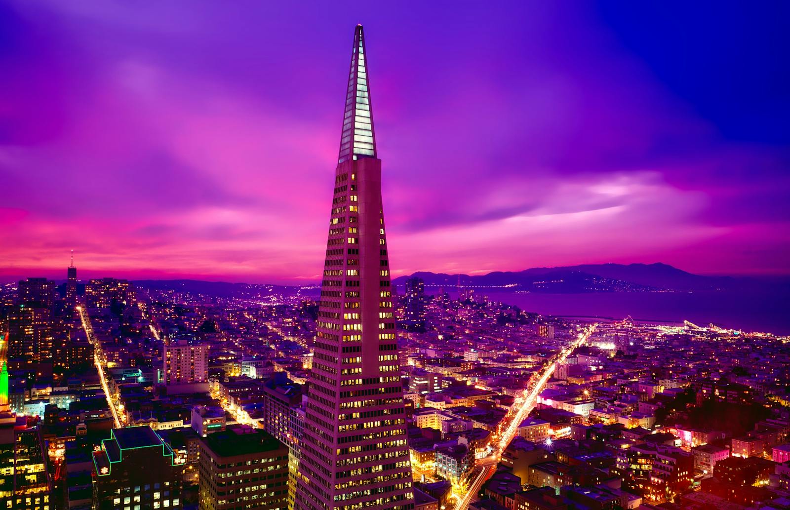 A vibrant view of San Francisco's skyline featuring the illuminated Transamerica Pyramid at sunset.