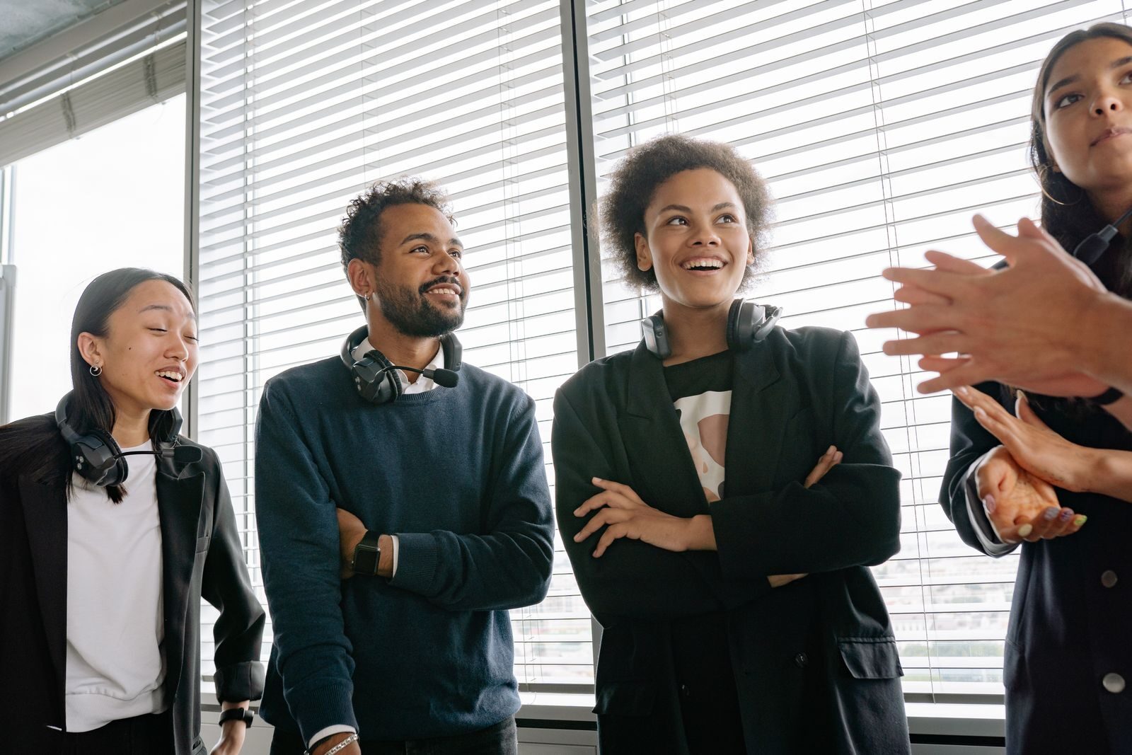 Group of diverse colleagues with headsets enjoying a conversation in a bright office setting.