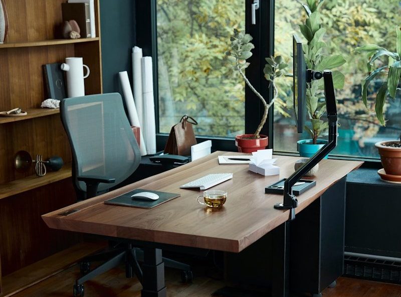 a desk with a laptop on it in front of a window
